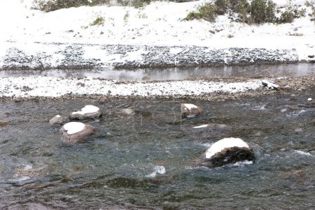 Téléchargez les photos : Pierres couvertes de neige en rivière en hiver - en image libre de droit