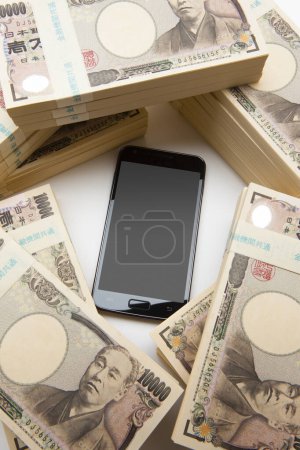 Téléchargez les photos : Smartphone avec de l'argent en yen japonais sur fond. vue de dessus. - en image libre de droit