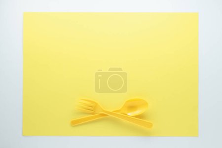 Foto de Vista superior de cubiertos de plástico brillante sobre fondo amarillo - Imagen libre de derechos