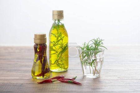 Photo for Glass bottles with oil and red peppers on wooden background - Royalty Free Image