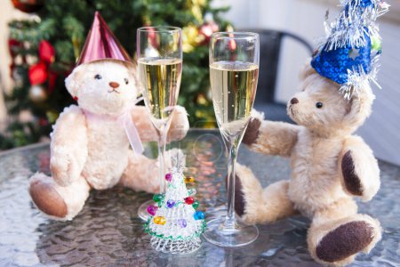 Foto de Vista de cerca de copas de champán y divertidos osos osos de peluche en sombreros de Navidad - Imagen libre de derechos