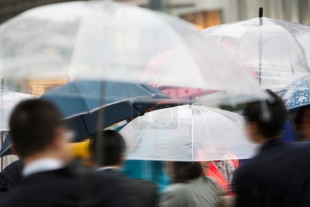 Foto de Visión borrosa de las personas con paraguas caminando por la calle de la ciudad bajo la lluvia - Imagen libre de derechos