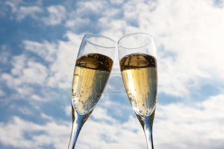 Téléchargez les photos : Flûtes à champagne avec bulles d'or contre ciel bleu - en image libre de droit