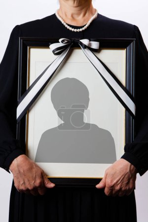 Vista de cerca de la persona que sostiene el marco funerario con silueta de hombre 