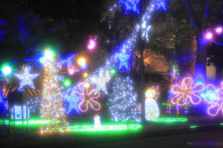 Téléchargez les photos : Fond de fête flou avec des lumières vives et des décorations de Noël dans la ville de nuit - en image libre de droit