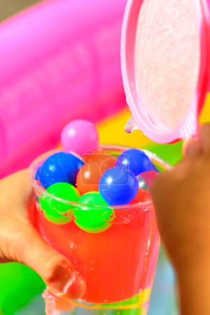 Photo for Children 's hand holding plastic cup with colorful small balls - Royalty Free Image