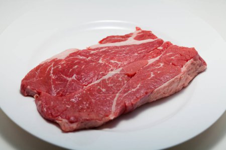 Téléchargez les photos : Steak de bœuf frais et cru sur assiette blanche - en image libre de droit