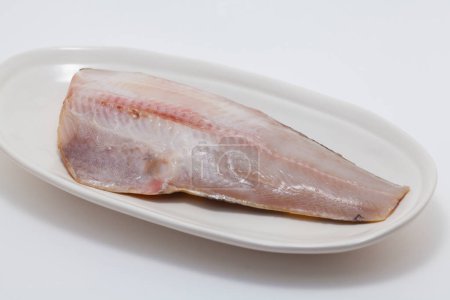 Foto de Pescado crudo en un plato sobre fondo blanco - Imagen libre de derechos