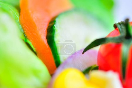 Photo for Salad with fresh vegetables, closeup. Cherry tomato, egg, slices of carrot and cucumber, lettuce leaves - Royalty Free Image