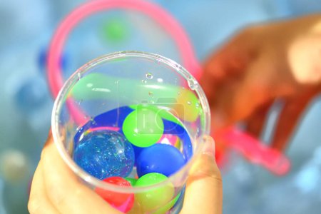 Photo for Children 's hand holding plastic cup with colorful small balls - Royalty Free Image