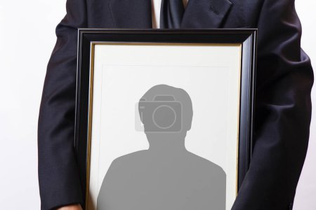 Téléchargez les photos : Vue rapprochée de la personne tenant un cadre funéraire avec silhouette homme - en image libre de droit