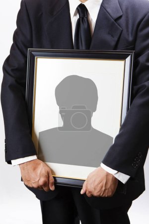 Photo for Close-up view of person holding funeral frame with man silhouette - Royalty Free Image