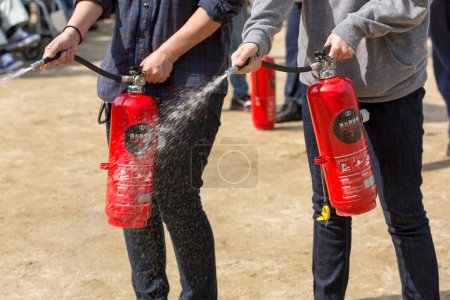 Photo for People with fire extinguishers in the city on background - Royalty Free Image