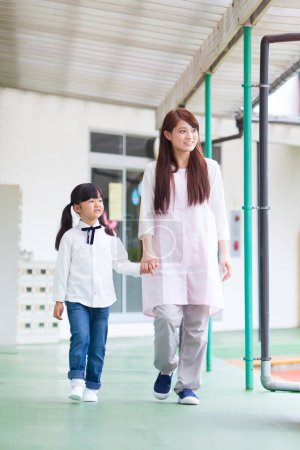 Asiatische Mutter und Tochter gehen in Schulflur 