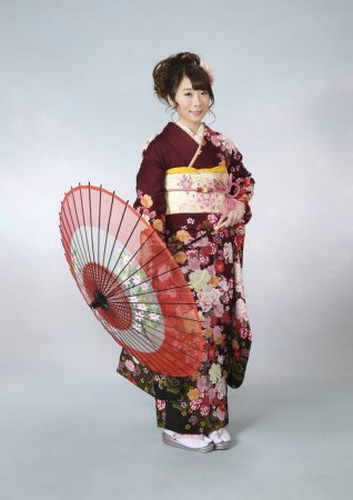 Foto de Retrato de hermosa joven japonesa en kimono tradicional con paraguas de papel antiguo - Imagen libre de derechos