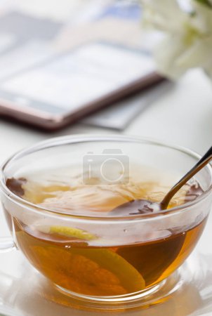 Téléchargez les photos : Une tasse de thé avec une tranche de citron dedans et smartphone - en image libre de droit
