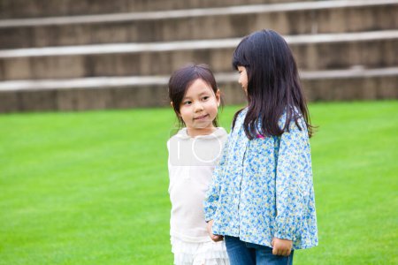 Foto de Retrato de dos niñas asiáticas sonrientes de pie sobre hierba verde - Imagen libre de derechos