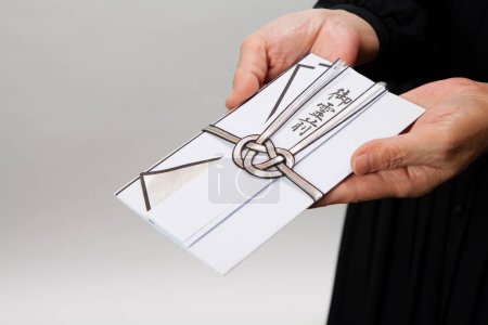 Téléchargez les photos : Sac traditionnel japonais enveloppant de l'argent pour les funérailles dans les mains - en image libre de droit