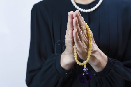 Téléchargez les photos : Femme assistant à des funérailles dans des vêtements de deuil avec des perles de prière - en image libre de droit
