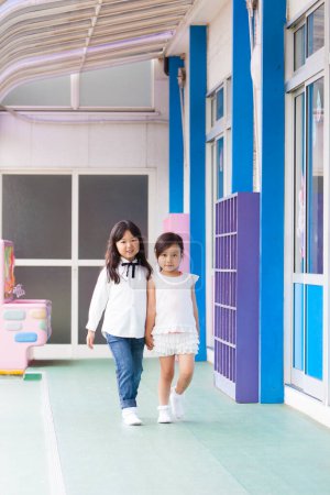 portrait of two Asian little girls walking in school corridor