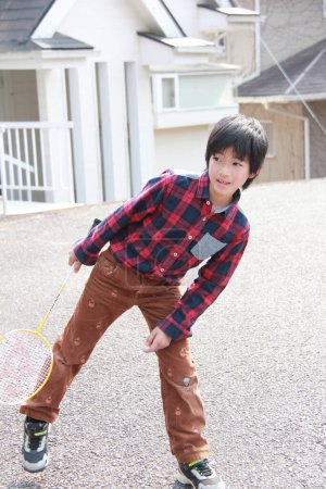 Téléchargez les photos : Japonais garçon jouer au badminton à l'arrière-cour - en image libre de droit