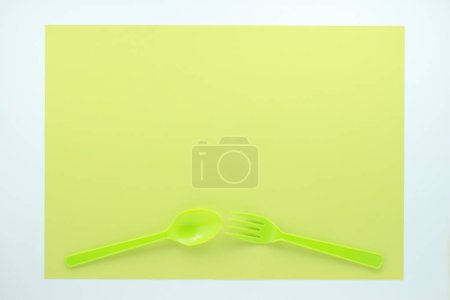 Foto de Vista superior de cubiertos de plástico brillante sobre fondo verde claro - Imagen libre de derechos