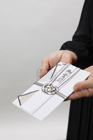 Téléchargez les photos : Sac traditionnel japonais enveloppant de l'argent pour les funérailles dans les mains - en image libre de droit