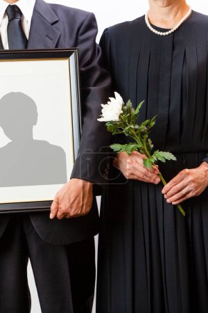 Photo for Close-up view of person holding funeral frame with man silhouette - Royalty Free Image