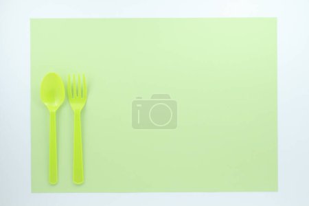 Foto de Vista superior de cubiertos de plástico brillante sobre fondo verde - Imagen libre de derechos