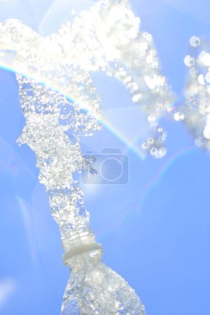 Téléchargez les photos : Éclaboussure d'eau de la bouteille sur le fond bleu ciel - en image libre de droit