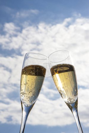 Téléchargez les photos : Flûtes à champagne avec bulles d'or contre ciel bleu - en image libre de droit