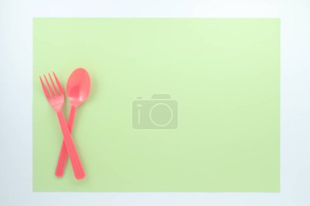 Photo for Top view of bright plastic cutlery on green background - Royalty Free Image