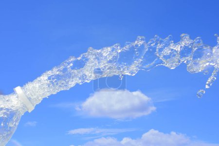 Téléchargez les photos : Éclaboussure d'eau de la bouteille sur le fond bleu ciel - en image libre de droit