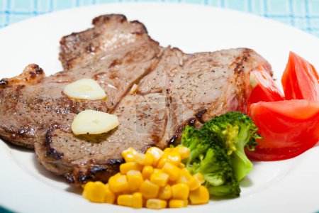 Téléchargez les photos : Vue rapprochée de délicieux steak grillé et légumes sur assiette blanche - en image libre de droit