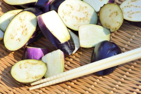 Photo for Sliced raw purple eggplants and chopsticks in basket, food background - Royalty Free Image