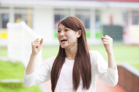 Photo for Portrait of excited Asian young woman clenching her fists happily outdoor - Royalty Free Image