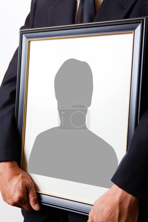 Vista de cerca de la persona que sostiene el marco funerario con silueta de hombre 