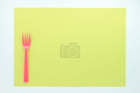 Photo for Top view of red plastic fork on yellow background - Royalty Free Image