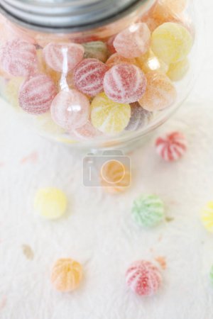Foto de Caramelos de jalea de colores y tarro de vidrio transparente en la mesa - Imagen libre de derechos
