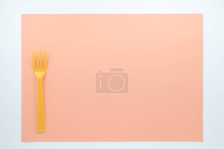 Foto de Vista superior de fondo beige tenedor de plástico naranja - Imagen libre de derechos