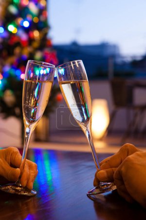 Photo for Close-up view of people clinking glasses of champagne on christmas background - Royalty Free Image