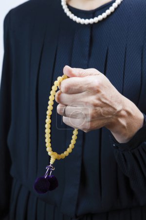 Téléchargez les photos : Femme assistant à des funérailles dans des vêtements de deuil avec des perles de prière - en image libre de droit
