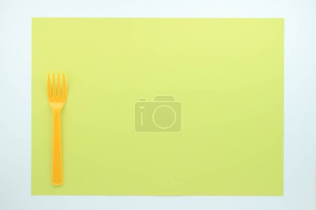 Téléchargez les photos : Vue de dessus de la fourche en plastique orange sur fond vert clair - en image libre de droit