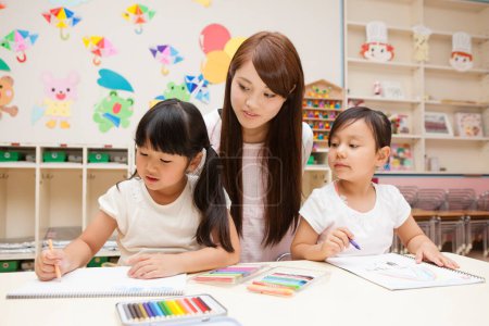 Foto de Retrato de feliz asiático joven profesor y dos niñas pequeño dibujo en el aula - Imagen libre de derechos
