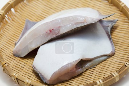 Téléchargez les photos : Filets de poisson crus sur un récipient en osier - en image libre de droit