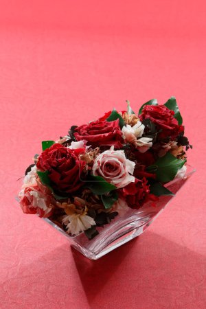 Téléchargez les photos : Belles roses roses et rouges dans un vase en verre sur fond rouge - en image libre de droit