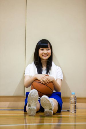 Foto de Japonés chica sentado en baloncesto cancha - Imagen libre de derechos