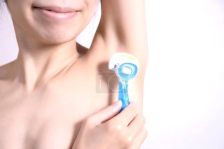Téléchargez les photos : Gros plan de femmes asiatiques rasage aisselles enlèvement des aisselles cheveux avec rasoir de sécurité - en image libre de droit