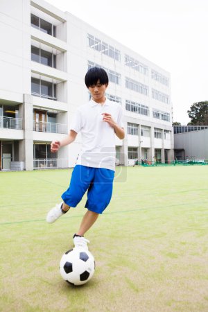 Foto de Joven japonés hombre jugando fútbol en el campo - Imagen libre de derechos