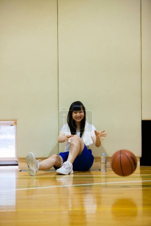 Téléchargez les photos : Mignonne asiatique fille assis sur basket-ball court - en image libre de droit